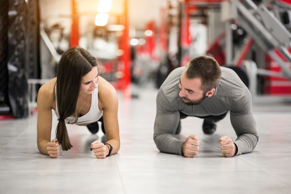 Mężczyzna i kobieta wykonują ćwiczenie Deski przeznaczone dla wszystkich grup mięśni